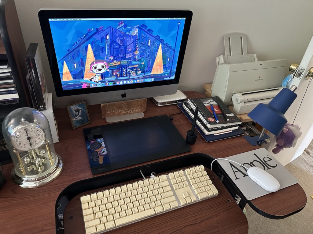 An iMac on my art desk, next to my two sketch books.