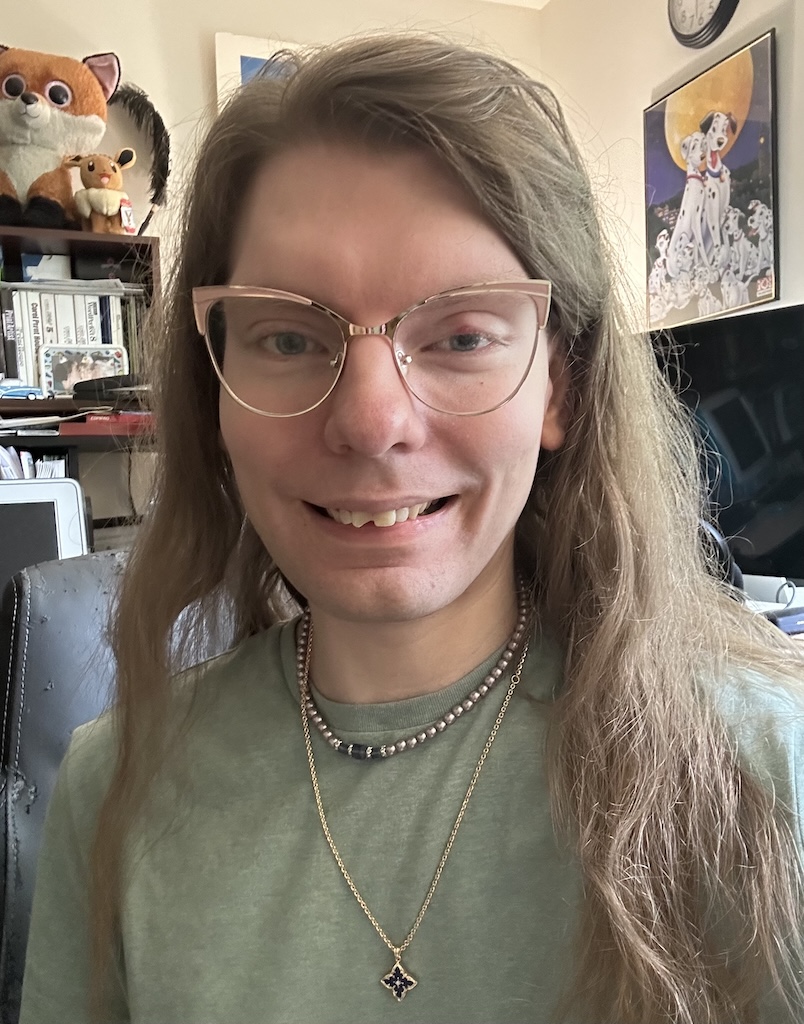 Spots IRL wearing a new collar, which is a gold necklace chain with a small sapphire pendant.