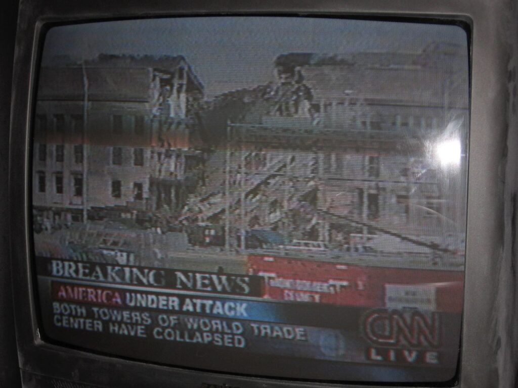 A television screen showing the aftermath of the plane crash into the Pentagon. Afternoon, 11th September 2001, Spots' living room.
